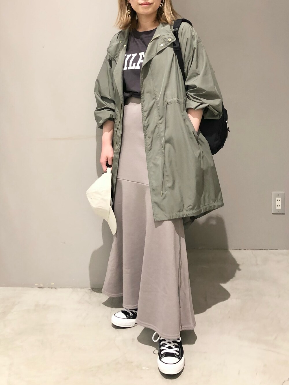 ブラウン系のスカート、ブラック系のスニーカー、グリーン系のモッズコートを着用したレディースの春コーディネートの1枚目の写真