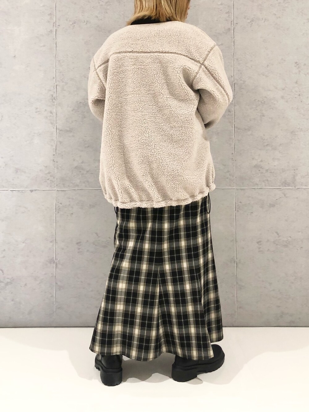 ブラック系のスカート、ブラック系のブーツ、ベージュ系のノーカラーコートを着用したレディースの冬コーディネートの3枚目の写真