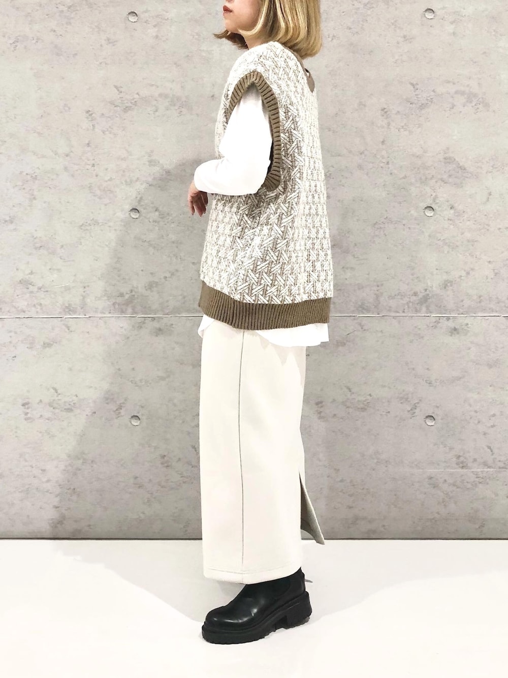 ベージュ系のスカート、ブラック系のブーツ、ホワイト系のTシャツ/カットソーを着用したレディースの冬コーディネートの3枚目の写真