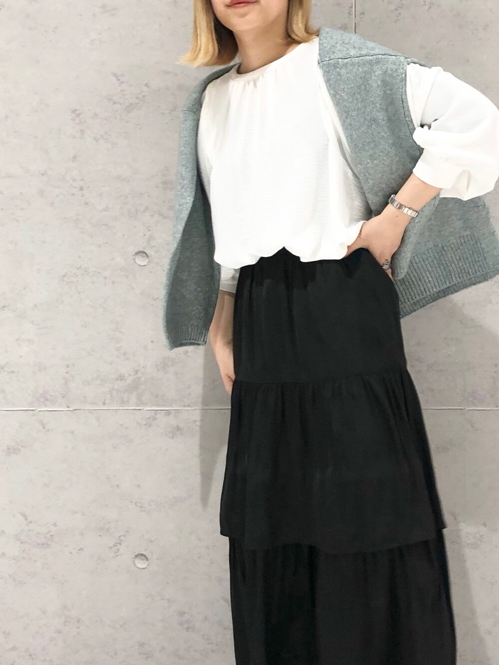 ホワイト系のシャツ/ブラウス、グリーン系のニット/セーター、ブラック系のスカートを着用したレディースの春コーディネートの2枚目の写真