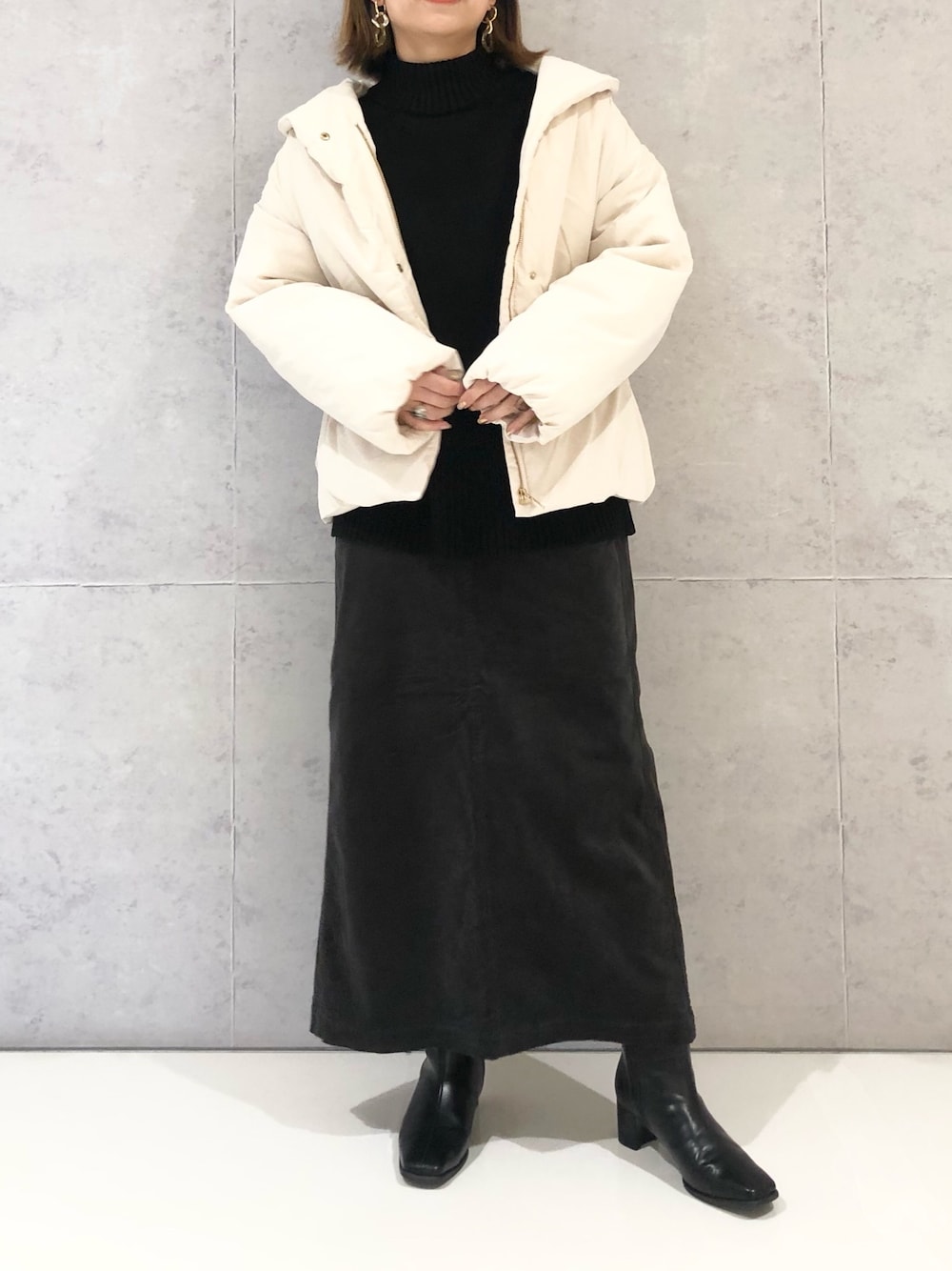 グレー系のスカート、ブラック系のブーツ、ブラック系のニット/セーターを着用したレディースの冬コーディネートの1枚目の写真