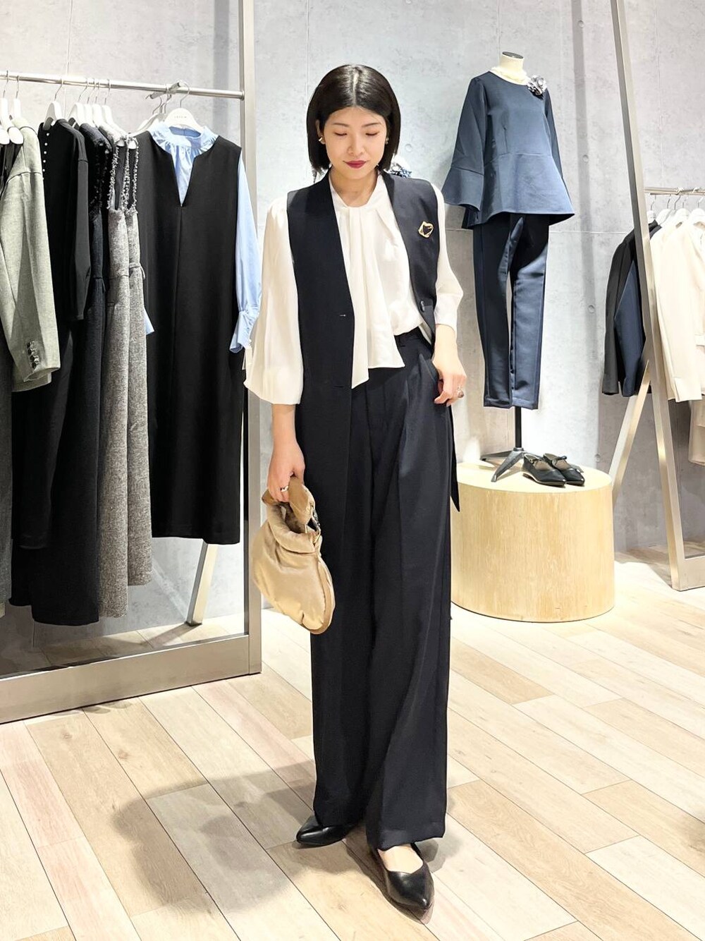 ベージュ系のハンドバッグ、ホワイト系のシャツ/ブラウス、ブラック系のパンプスを着用したレディースの冬コーディネートの1枚目の写真