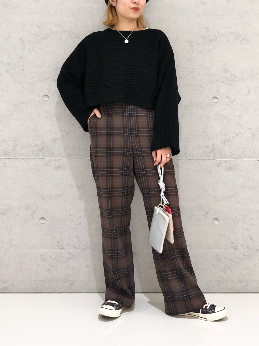 グレー系のスニーカー、シルバー系のショルダーバッグ、ブラック系のニット/セーターを着用したレディースの冬コーディネートの2枚目の写真