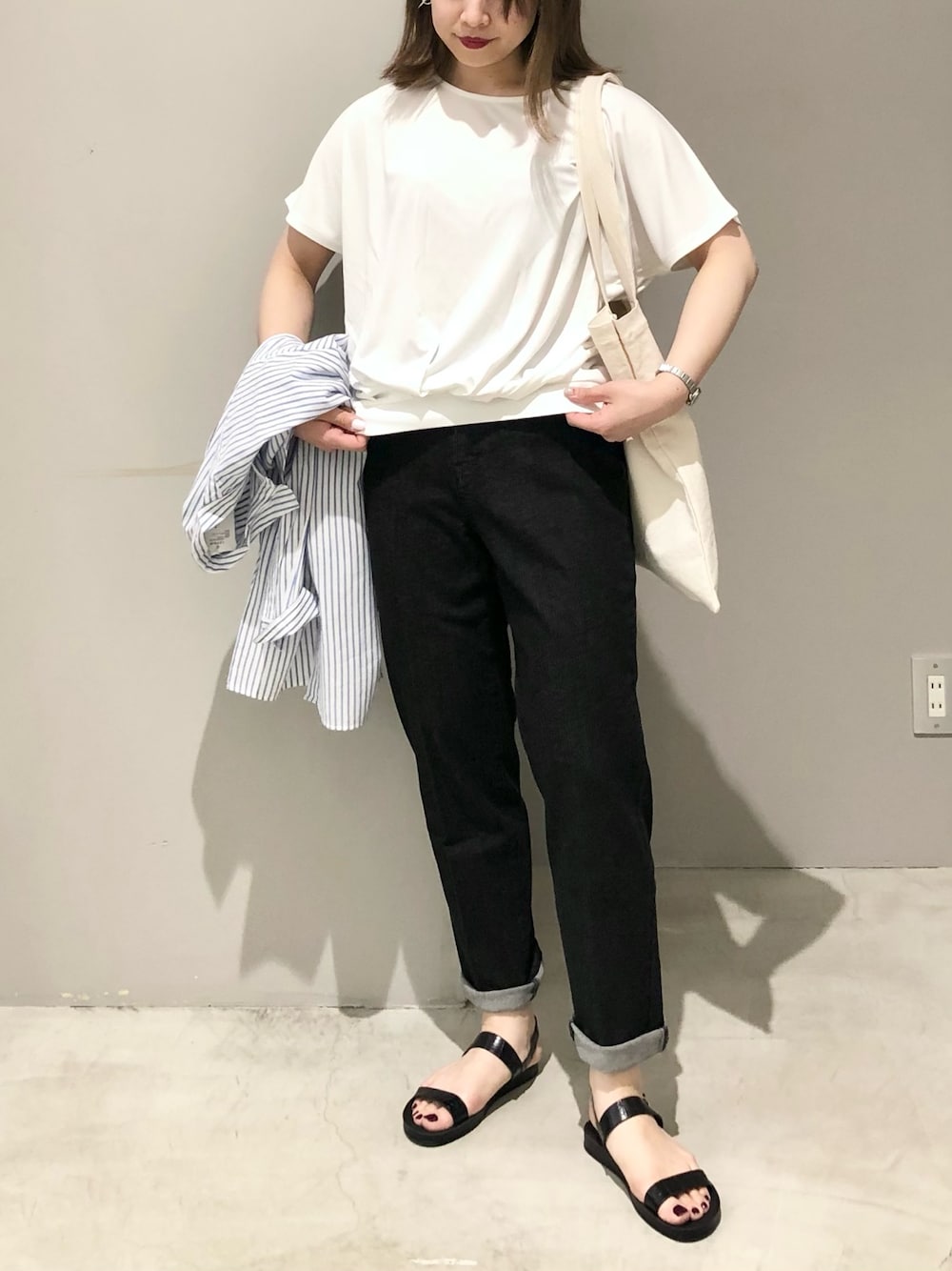 ホワイト系のトートバッグ、ブラック系のデニムパンツ、ホワイト系のTシャツ/カットソーを着用したレディースの夏コーディネートの2枚目の写真