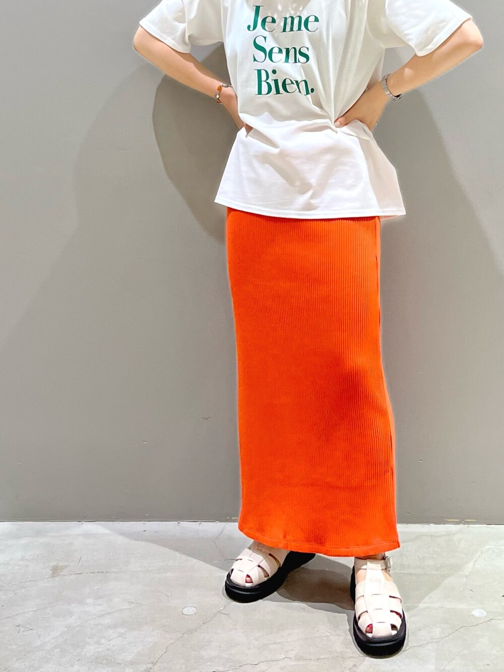 オレンジ系のスカート、ホワイト系のサンダル、グリーン系のTシャツ/カットソーを着用したレディースの夏コーディネートの3枚目の写真