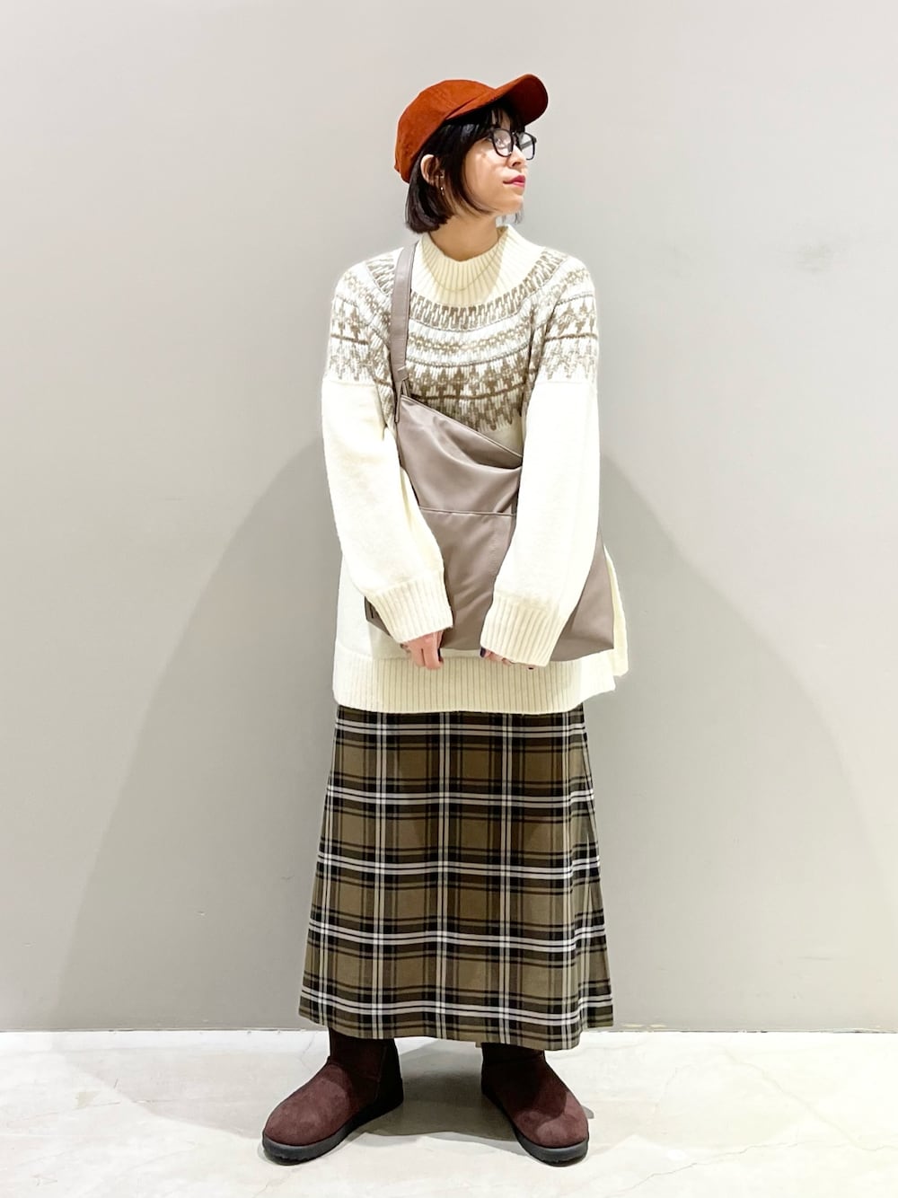 ブラウン系のスカート、ブラウン系のブーツ、ベージュ系のショルダーバッグを着用したレディースの冬コーディネートの1枚目の写真