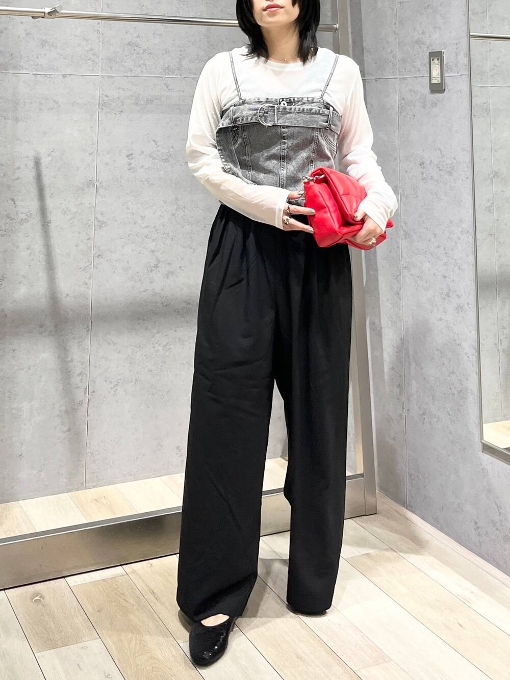 レッド系のショルダーバッグ、ブラック系のスラックス、ブラック系のバレエシューズを着用したレディースの夏コーディネートの1枚目の写真