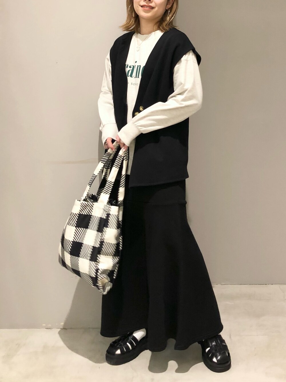 ブラック系のスカート、ブラック系のショルダーバッグ、ブラック系のサンダルを着用したレディースの春コーディネートの1枚目の写真