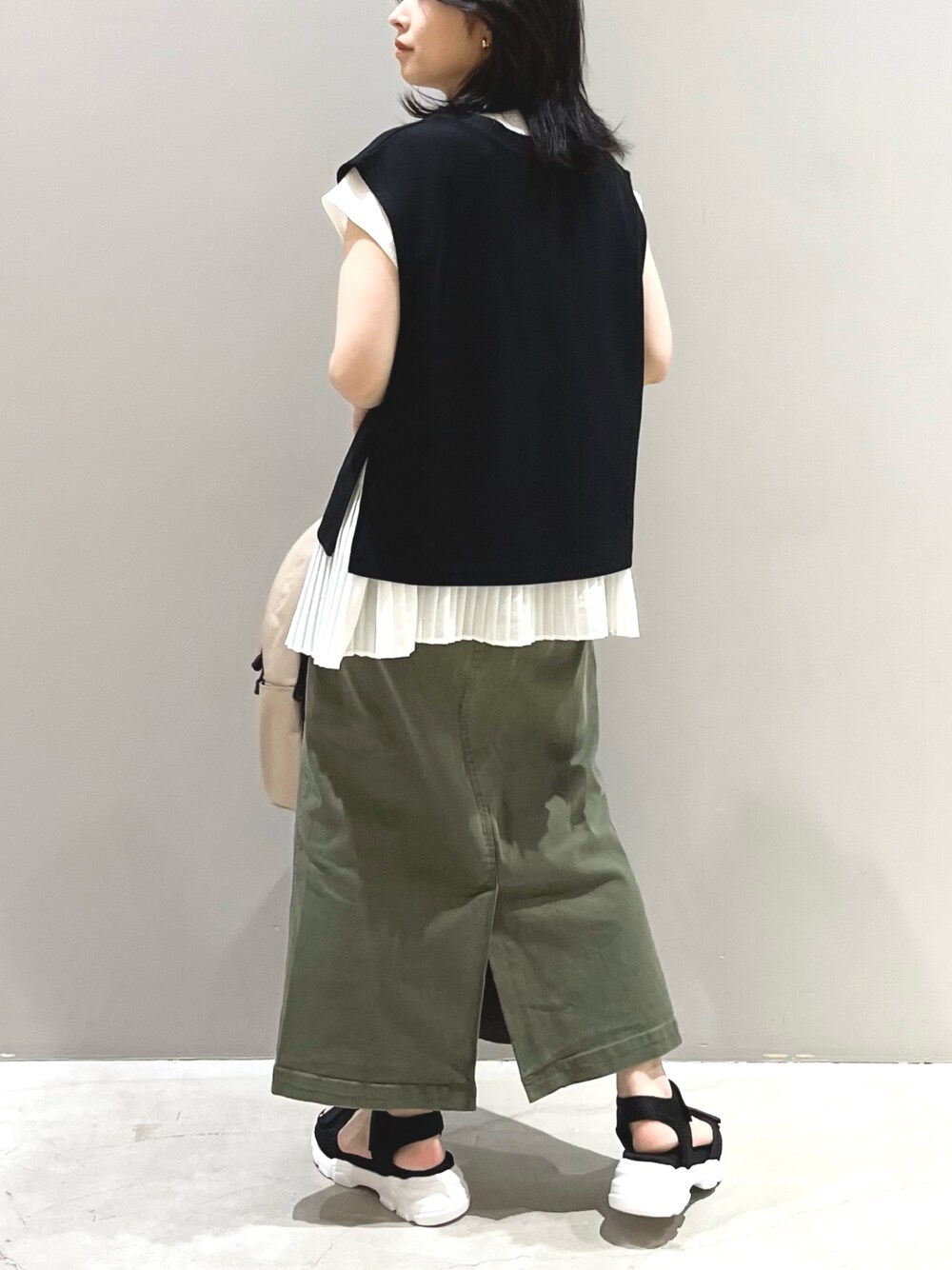 ブラック系のベスト、ホワイト系のシャツ/ブラウス、グリーン系のスカートを着用したレディースの夏コーディネートの2枚目の写真