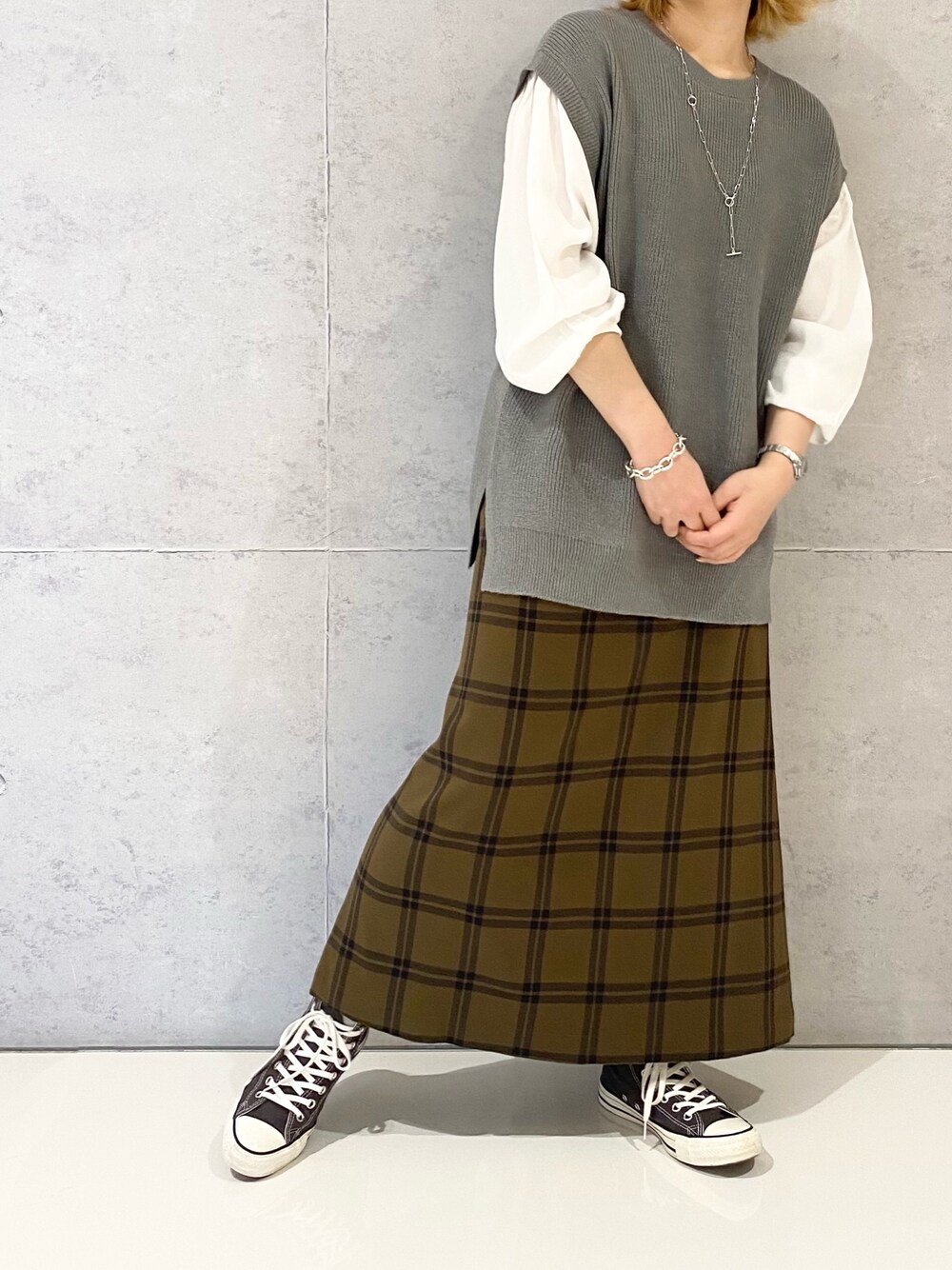 グレー系のニット/セーター、ブラウン系のスカート、グレー系のスニーカーを着用したレディースの冬コーディネートの2枚目の写真