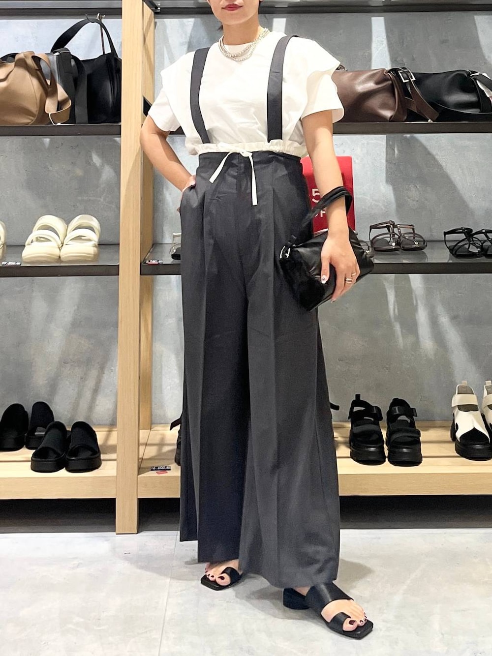 ブラック系のハンドバッグ、ブラック系のサンダル、ホワイト系のTシャツ/カットソーを着用したレディースの夏コーディネートの1枚目の写真