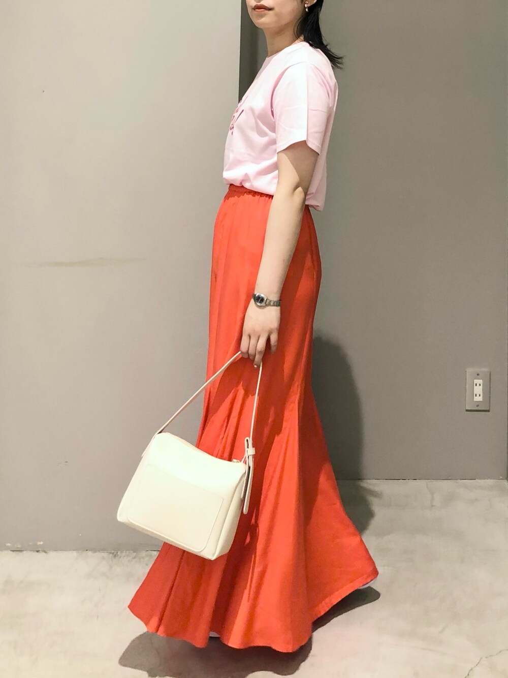 ホワイト系のショルダーバッグ、オレンジ系のスカート、ピンク系のTシャツ/カットソーを着用したレディースの夏コーディネートの1枚目の写真