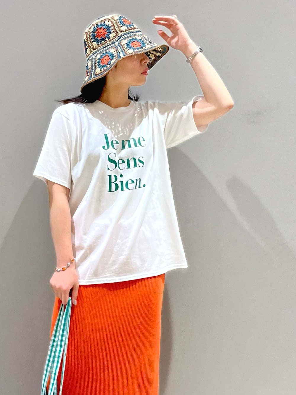 オレンジ系のスカート、ホワイト系のサンダル、グリーン系のTシャツ/カットソーを着用したレディースの夏コーディネートの2枚目の写真