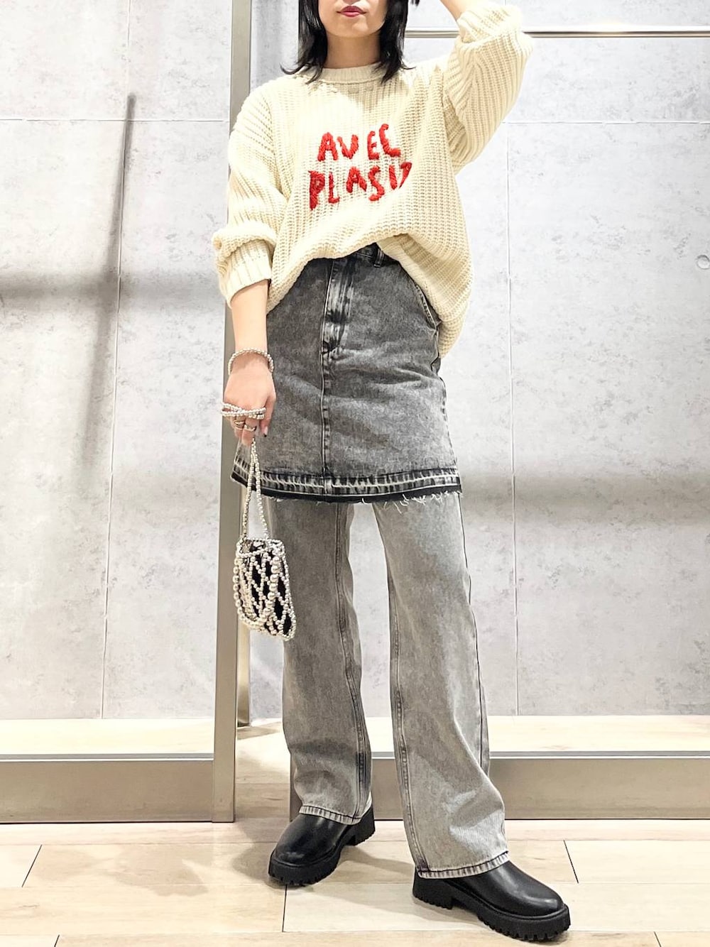 シルバー系のショルダーバッグ、ブラック系のデニムパンツ、ブラック系のブーツを着用したレディースの秋コーディネートの1枚目の写真