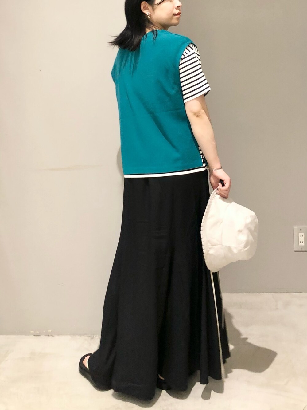 ホワイト系のサンダル、ブラック系のスカート、グリーン系のベストを着用したレディースの夏コーディネートの3枚目の写真