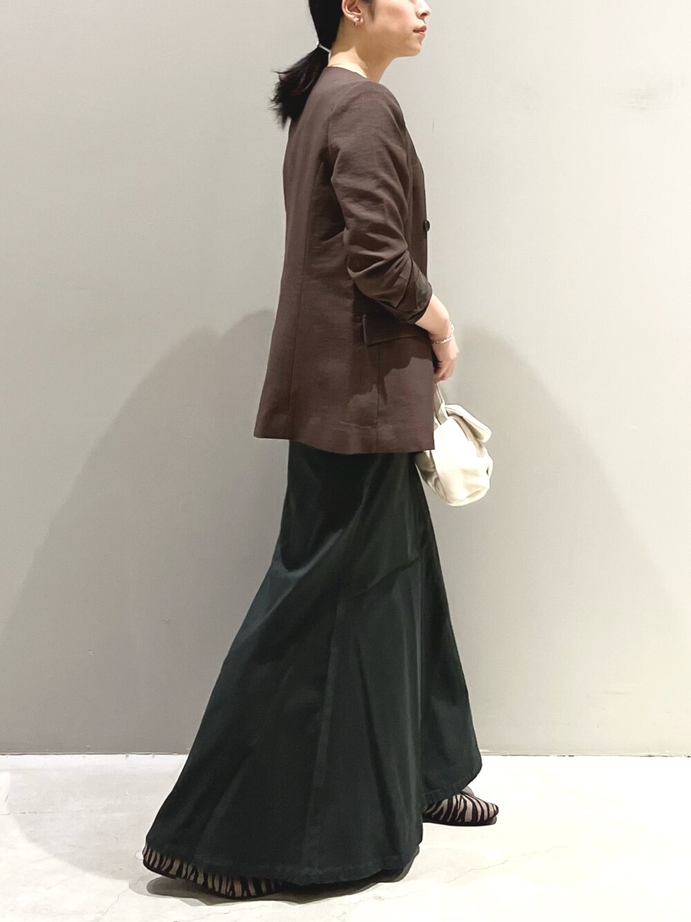 グレー系のスカート、その他のパンプス、ブラウン系のジャケット/アウターを着用したレディースの夏コーディネートの2枚目の写真