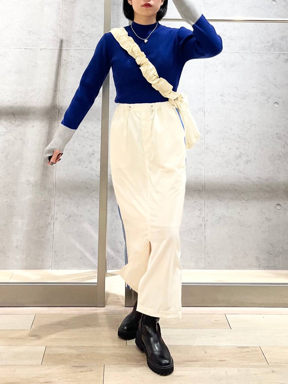 ブラック系のブーツ、ホワイト系のショルダーバッグ、ホワイト系のスカートを着用したレディースの冬コーディネートの1枚目の写真