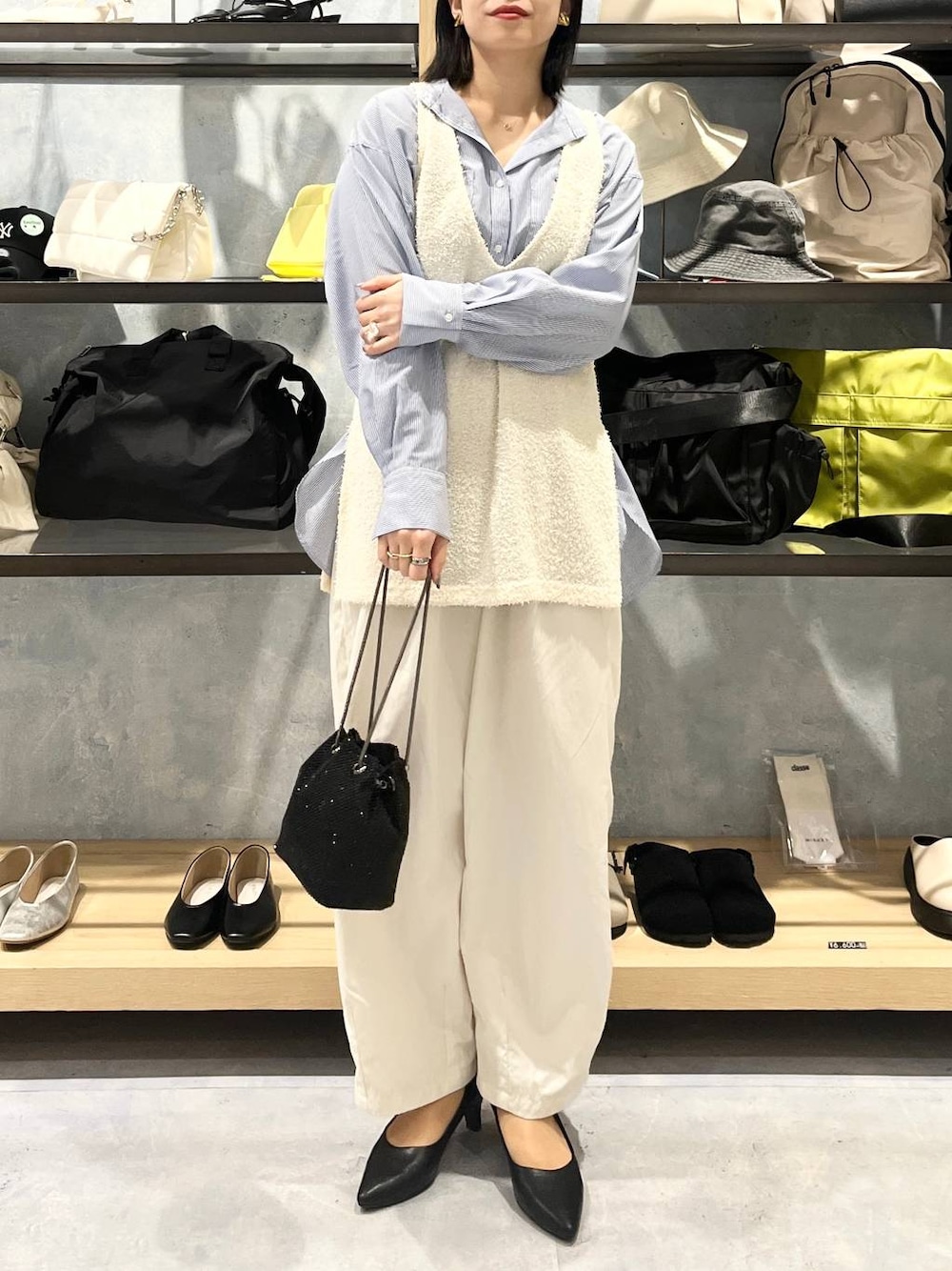 ブラック系のショルダーバッグ、ブラック系のパンプス、ブルー系のシャツ/ブラウスを着用したレディースの春コーディネートの1枚目の写真