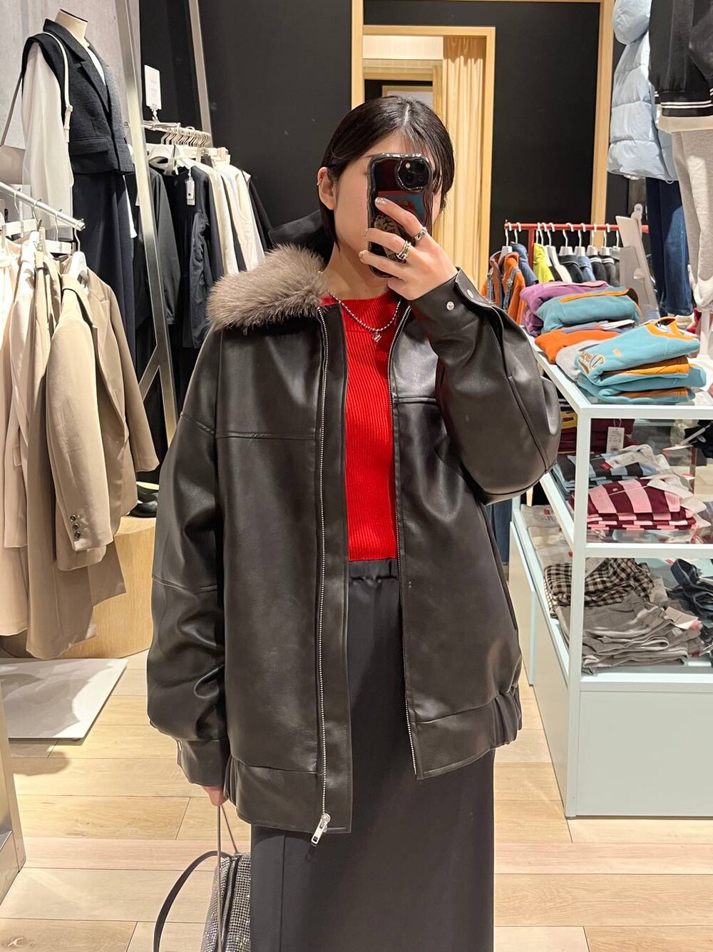 ブラック系のブーツ、オレンジ系のニット/セーター、ブラック系のスカートを着用したレディースの冬コーディネートの1枚目の写真