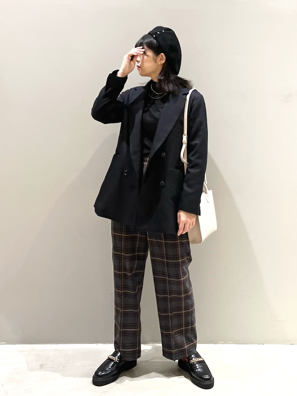 ブラウン系のスラックス、ブラック系のローファー、ホワイト系のショルダーバッグを着用したレディースの秋コーディネートの1枚目の写真