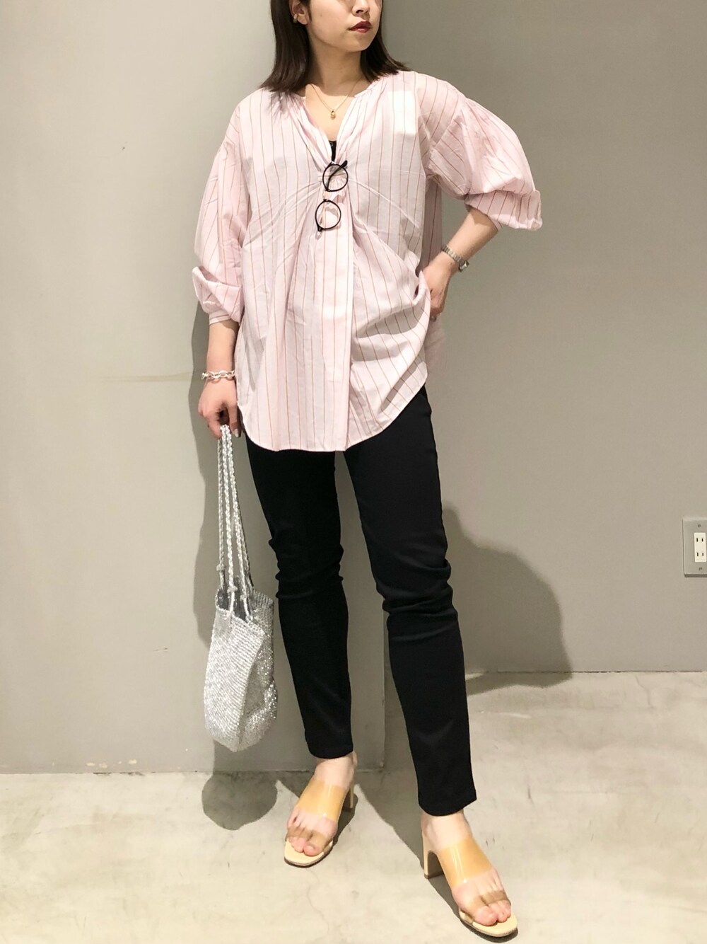 ブラック系のパンツ、イエロー系のサンダル、シルバー系のショルダーバッグを着用したレディースの春コーディネートの3枚目の写真