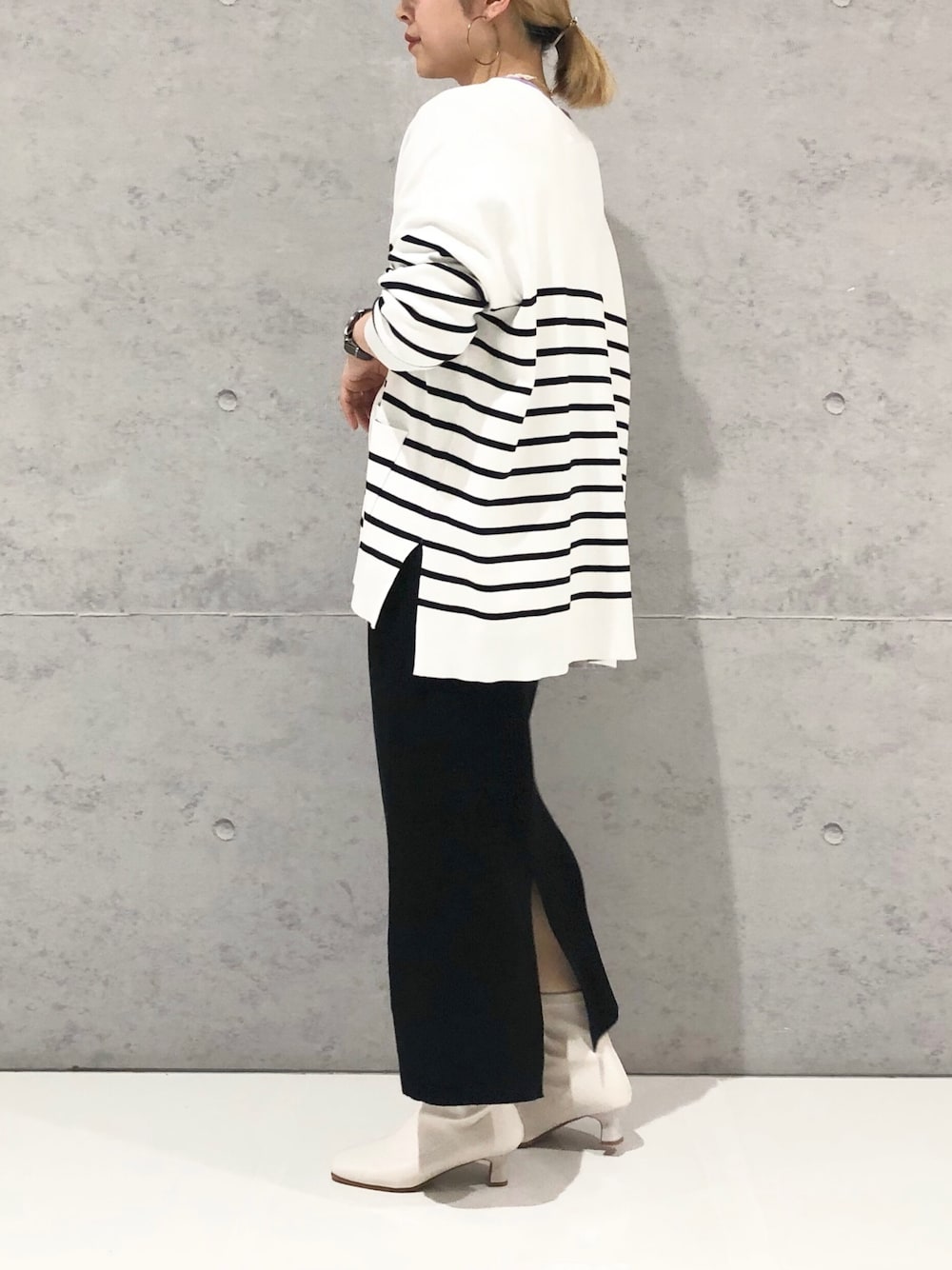ブラック系のスカート、ホワイト系のブーツ、ホワイト系のカーディガン/ボレロを着用したレディースの冬コーディネートの3枚目の写真