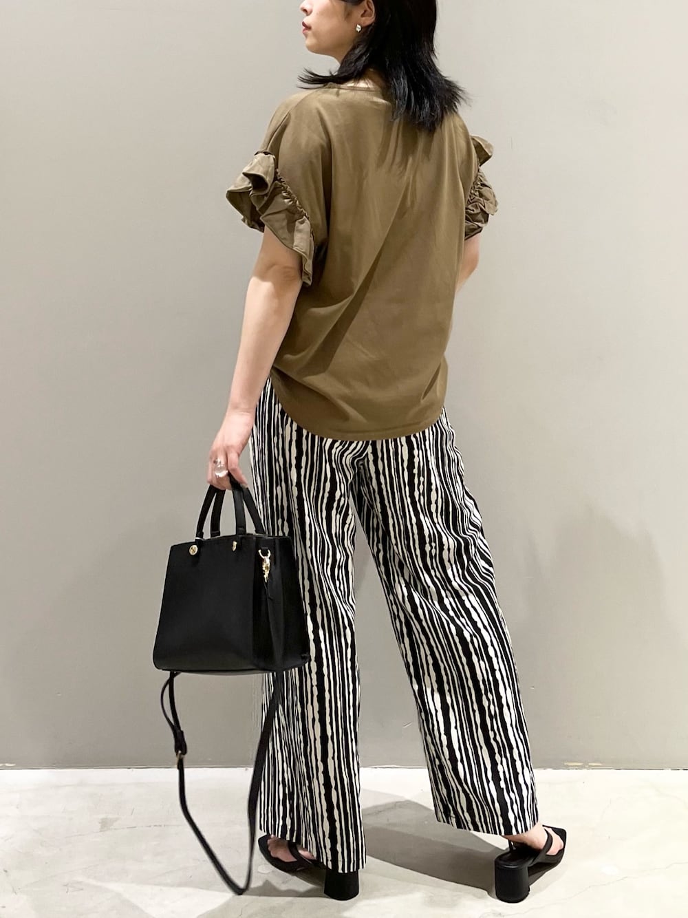 グリーン系のTシャツ/カットソー、ブラック系のサンダル、ブラック系のショルダーバッグを着用したレディースの夏コーディネートの3枚目の写真