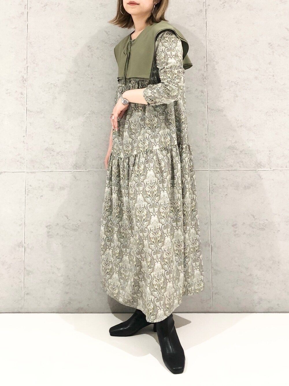 グリーン系のワンピース、グリーン系のTシャツ/カットソー、ブラック系のブーツを着用したレディースの冬コーディネートの3枚目の写真