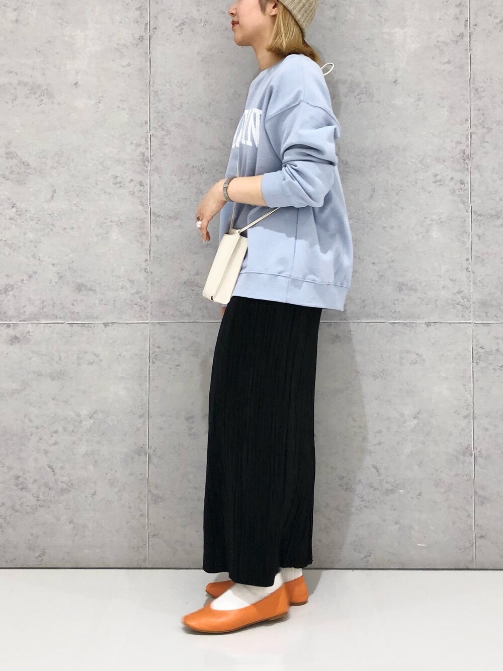 ホワイト系のショルダーバッグ、オレンジ系のパンプス、ブルー系のスウェットを着用したレディースの冬コーディネートの3枚目の写真