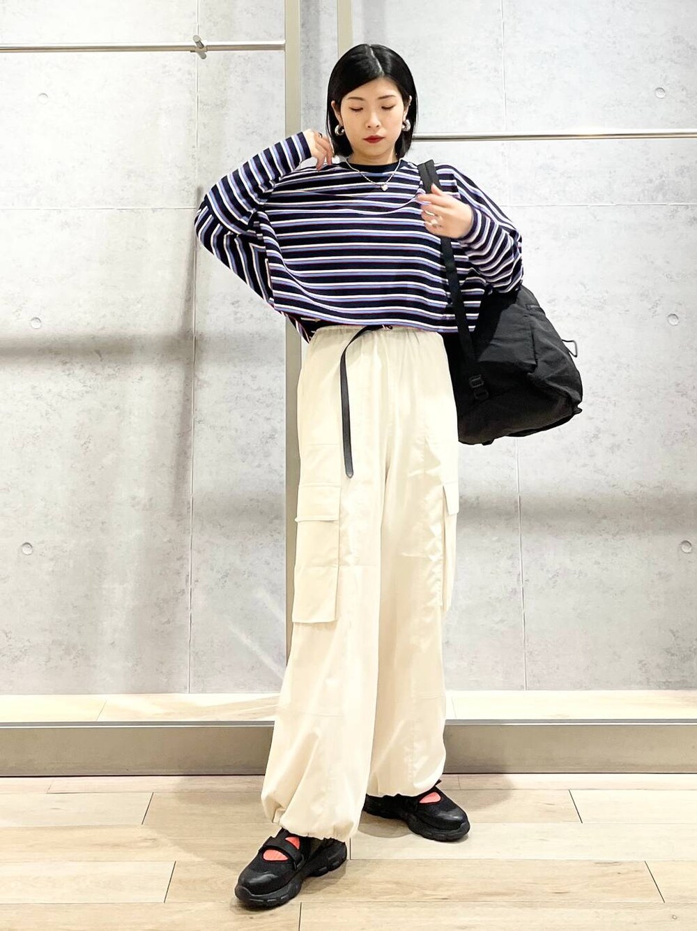 ブラック系のショルダーバッグ、ブルー系のTシャツ/カットソー、ホワイト系のカーゴパンツを着用したレディースの春コーディネートの1枚目の写真