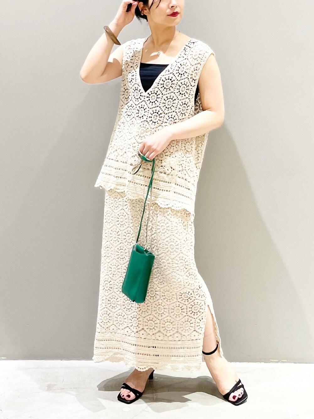 ブラック系のサンダル、グリーン系のショルダーバッグ、ブラック系のタンクトップを着用したレディースの夏コーディネートの2枚目の写真