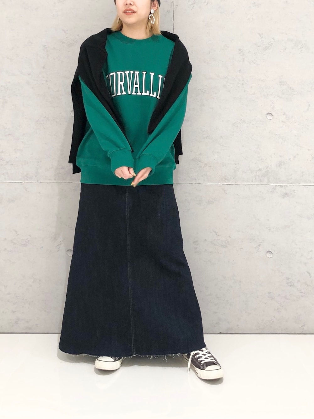 グリーン系のスウェット、ブラック系のカーディガン/ボレロ、ブラック系のスカートを着用したレディースの冬コーディネートの2枚目の写真