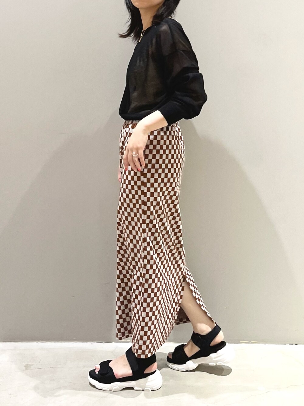 ブラック系のサンダル、ブラック系のニット/セーター、ゴールド系のイヤリングを着用したレディースの夏コーディネートの3枚目の写真