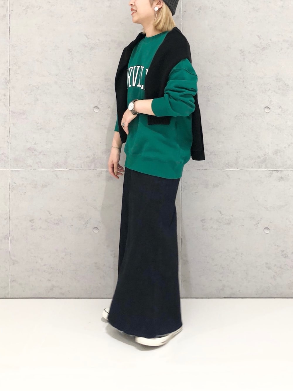 グリーン系のスウェット、ブラック系のカーディガン/ボレロ、ブラック系のスカートを着用したレディースの冬コーディネートの3枚目の写真