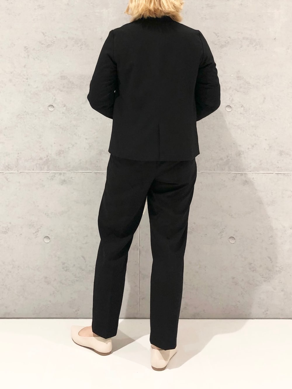 ホワイト系のハンドバッグ、ホワイト系のパンプス、ブラック系のスラックスを着用したレディースの冬コーディネートの4枚目の写真