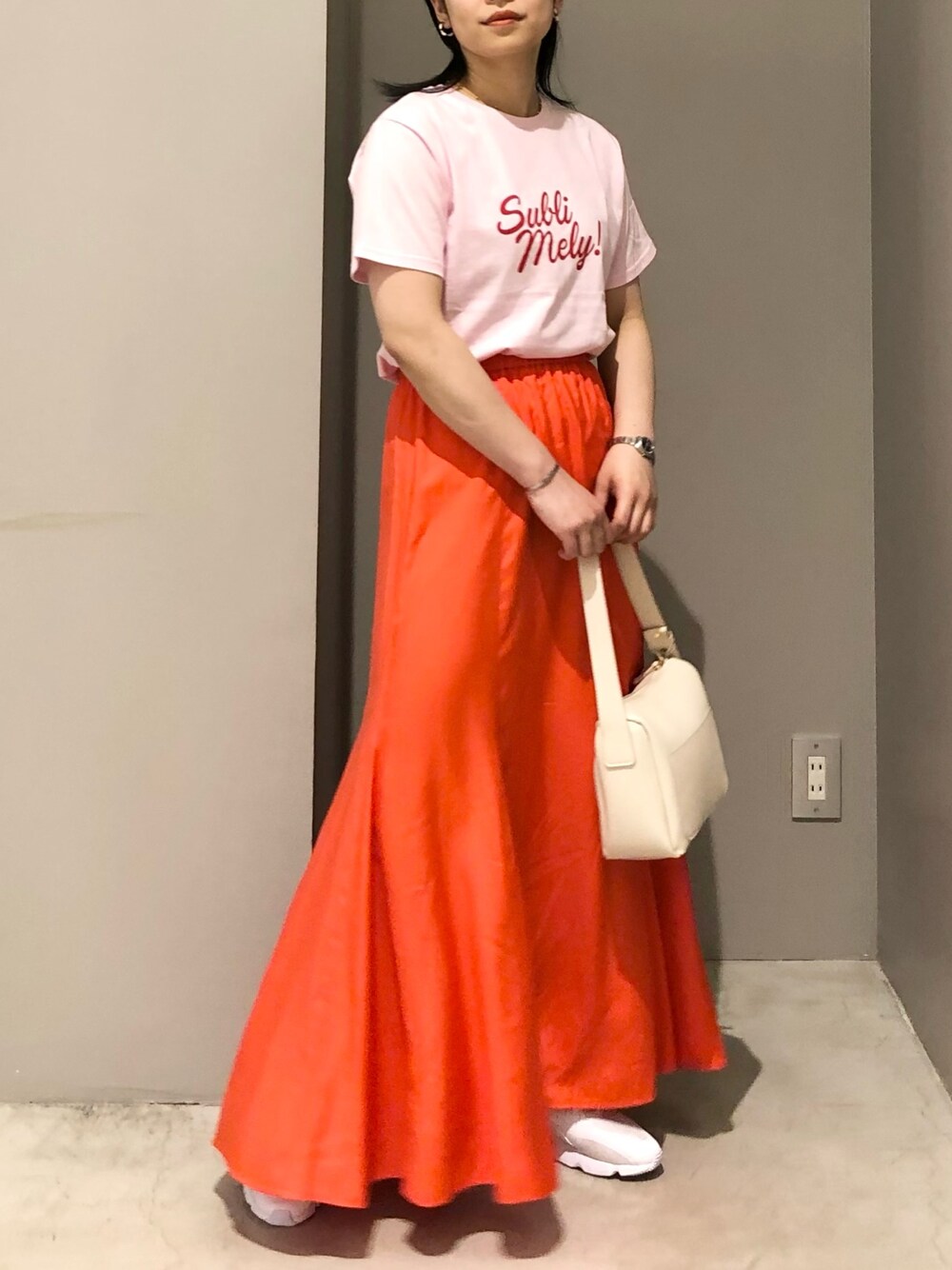ホワイト系のショルダーバッグ、オレンジ系のスカート、ピンク系のTシャツ/カットソーを着用したレディースの夏コーディネートの2枚目の写真