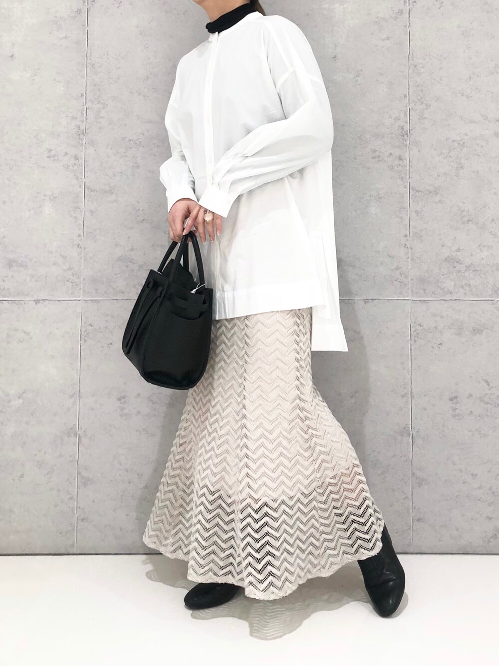 ベージュ系のスカート、ブラック系のショルダーバッグ、ブラック系のブーツを着用したレディースの冬コーディネートの2枚目の写真