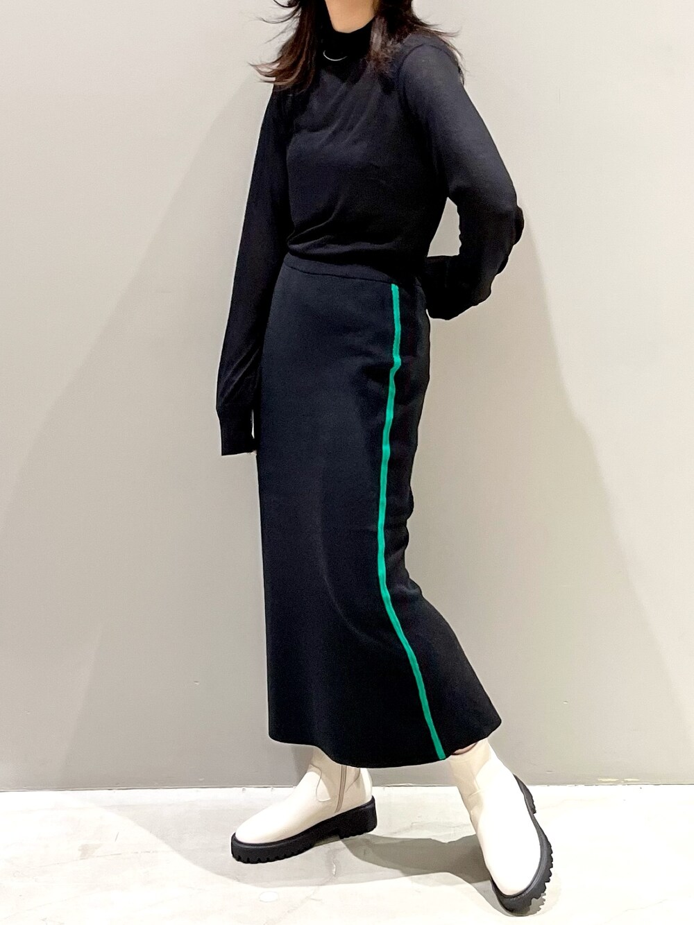 ブラック系のスカート、ホワイト系のブーツ、ブラック系のTシャツ/カットソーを着用したレディースの秋コーディネートの2枚目の写真