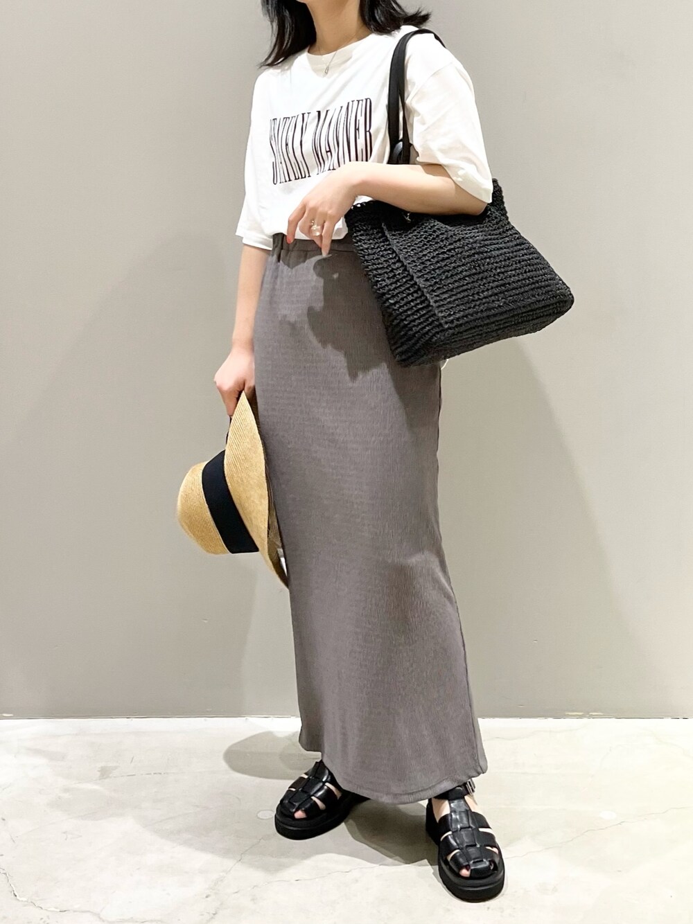 ブラウン系のスカート、ブラック系のサンダル、ホワイト系のTシャツ/カットソーを着用したレディースの夏コーディネートの1枚目の写真