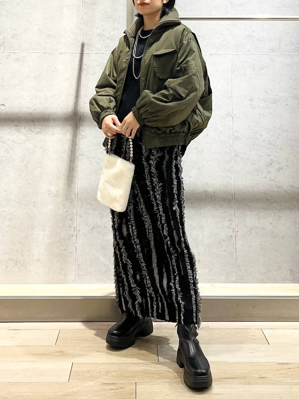 ブラック系のスカート、ブラック系のTシャツ/カットソー、ブラック系のブーツを着用したレディースの秋コーディネートの1枚目の写真