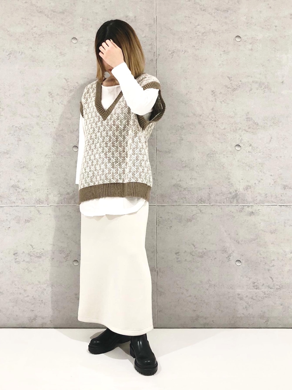 ベージュ系のスカート、ブラック系のブーツ、ホワイト系のTシャツ/カットソーを着用したレディースの冬コーディネートの2枚目の写真