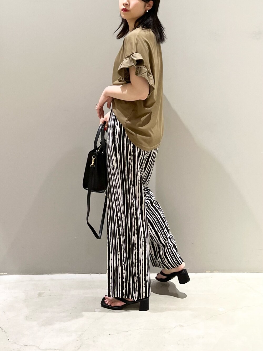 グリーン系のTシャツ/カットソー、ブラック系のサンダル、ブラック系のショルダーバッグを着用したレディースの夏コーディネートの4枚目の写真