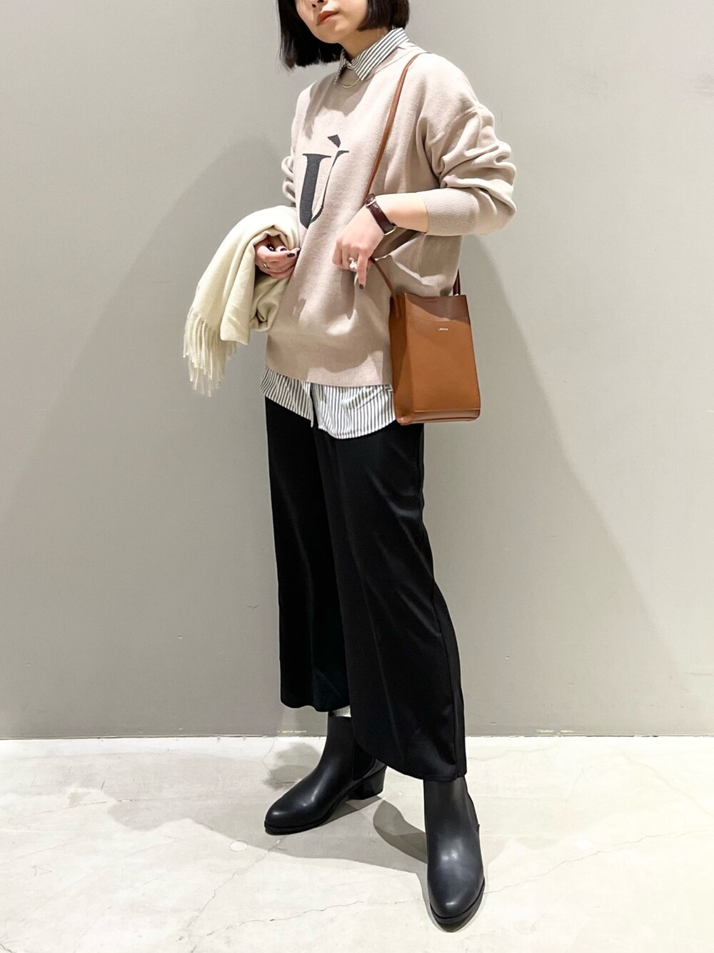 ブラック系のスカート、ブラック系のブーツ、ブラウン系のショルダーバッグを着用したレディースの冬コーディネートの1枚目の写真