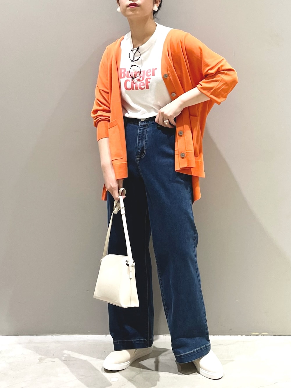 ブルー系のデニムパンツ、ホワイト系のシューズ、ホワイト系のショルダーバッグを着用したレディースの夏コーディネートの1枚目の写真