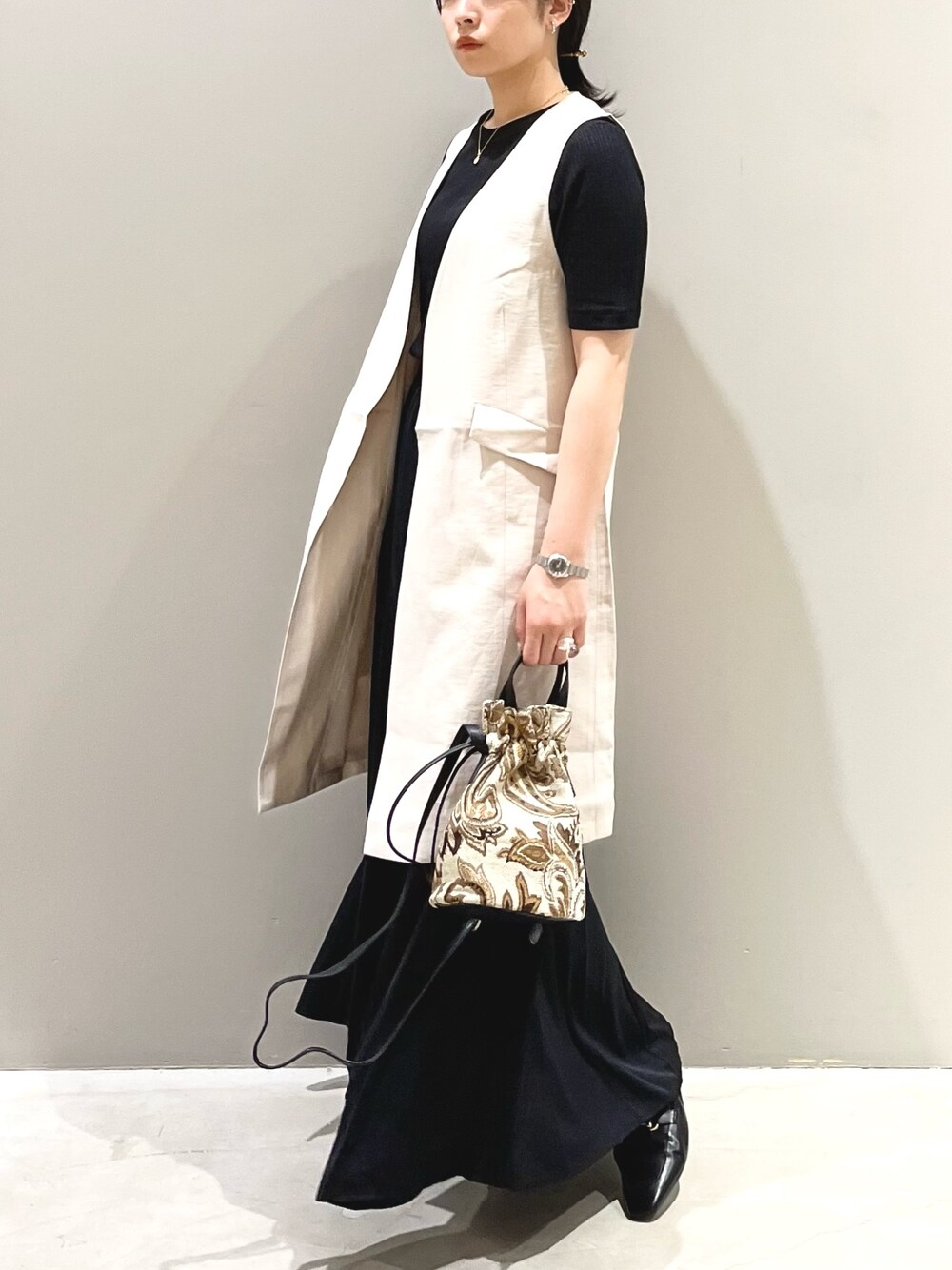 ブラウン系のショルダーバッグ、ブラック系のローファー、ブラック系のスカートを着用したレディースの夏コーディネートの4枚目の写真