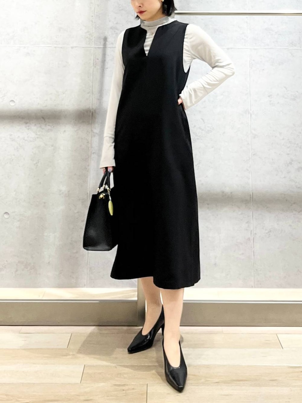 ブラック系のパンプス、グレー系のTシャツ/カットソー、ブラック系のショルダーバッグを着用したレディースの冬コーディネートの1枚目の写真