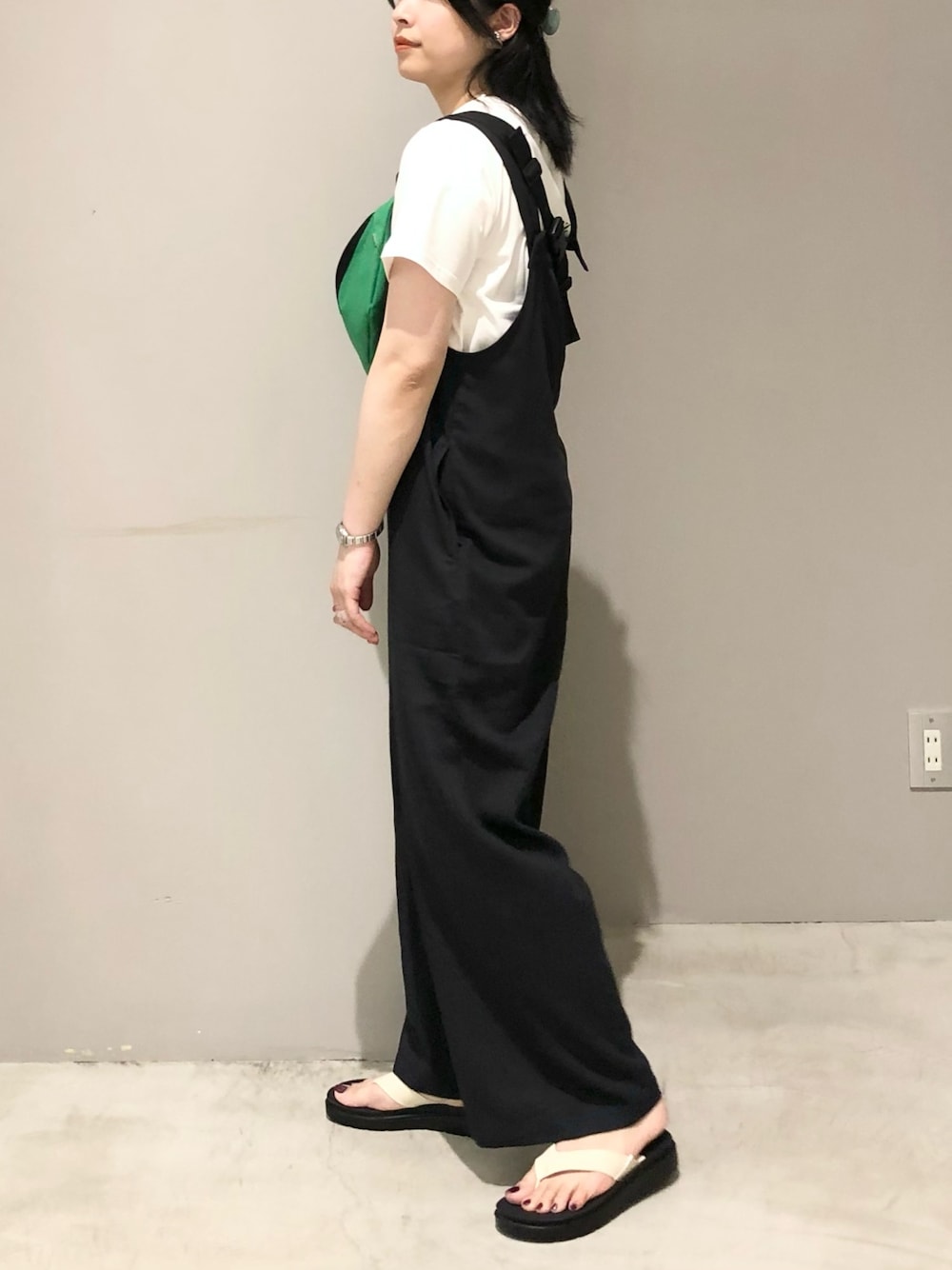 ブラック系のサロペット/オーバーオール、ホワイト系のサンダル、ホワイト系のTシャツ/カットソーを着用したレディースの夏コーディネートの2枚目の写真