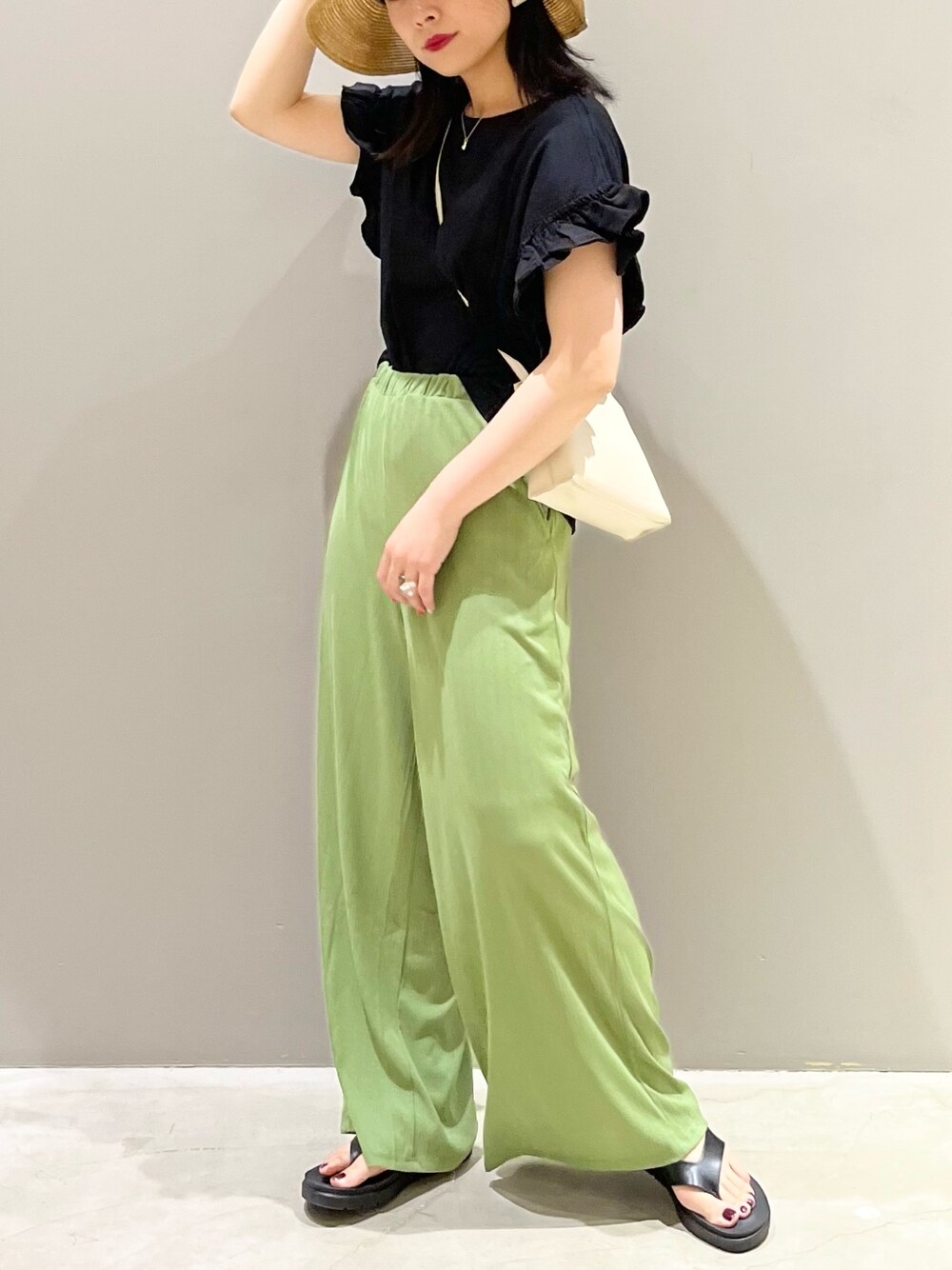 グリーン系のパンツ、ホワイト系のショルダーバッグ、ブラック系のTシャツ/カットソーを着用したレディースの夏コーディネートの2枚目の写真