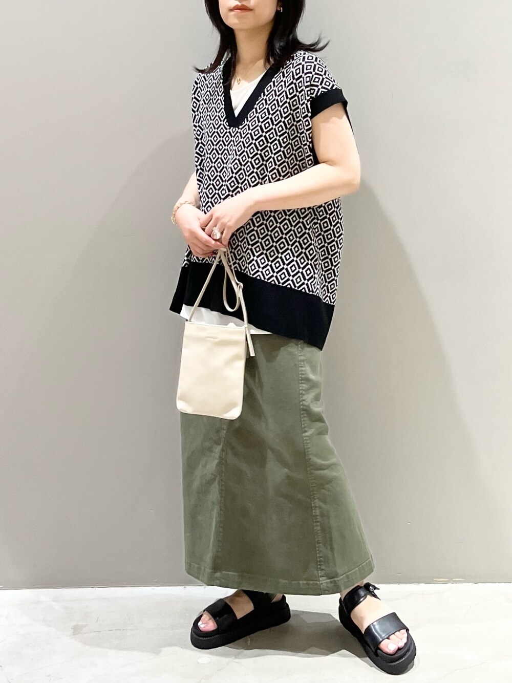 グリーン系のスカート、ブラック系のサンダル、ホワイト系のバッグを着用したレディースの夏コーディネートの2枚目の写真