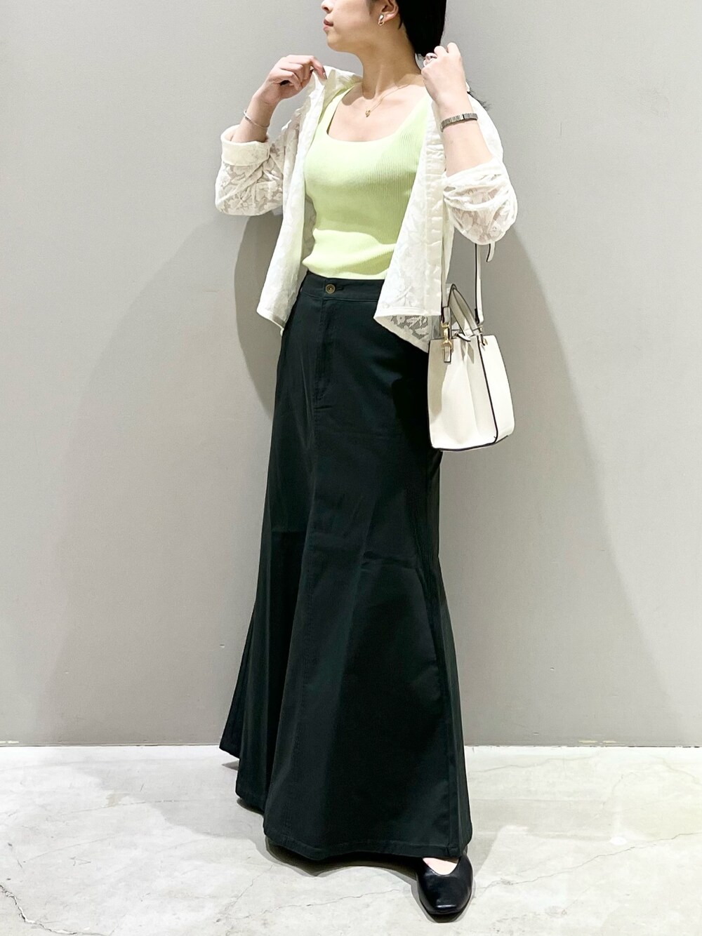 ブラック系のパンプス、グレー系のスカート、ホワイト系のショルダーバッグを着用したレディースの秋コーディネートの1枚目の写真